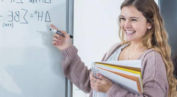 Student pointing toward math equation on white board